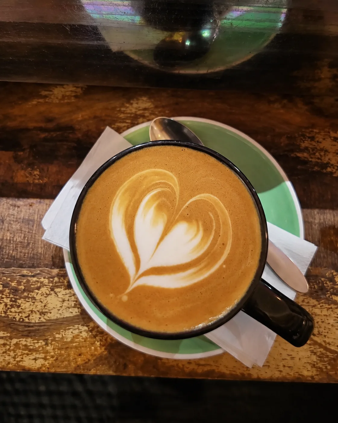 A flat white served on a wooden cafe table